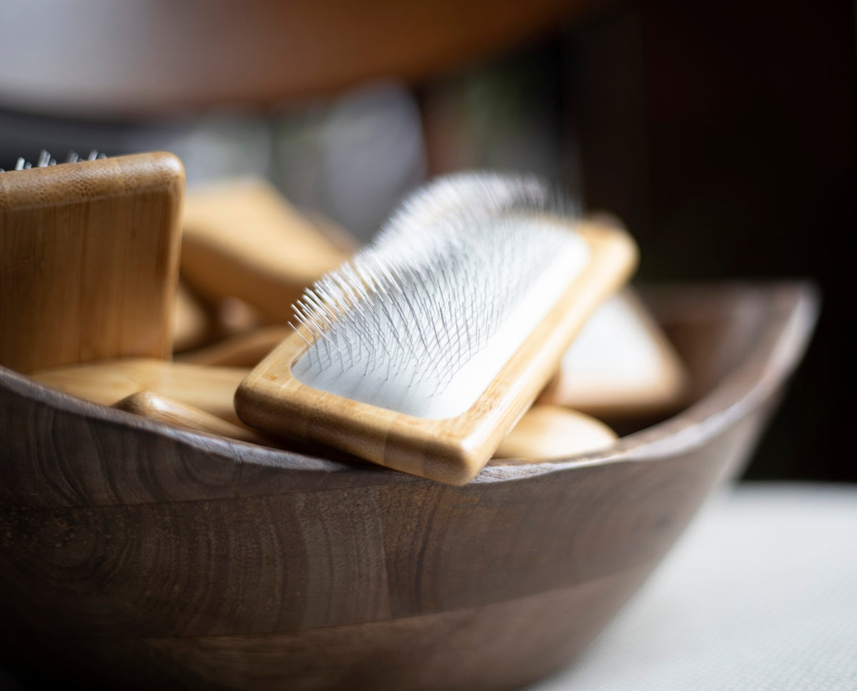 a wooden bowl filled with wooden brushes on top of a table