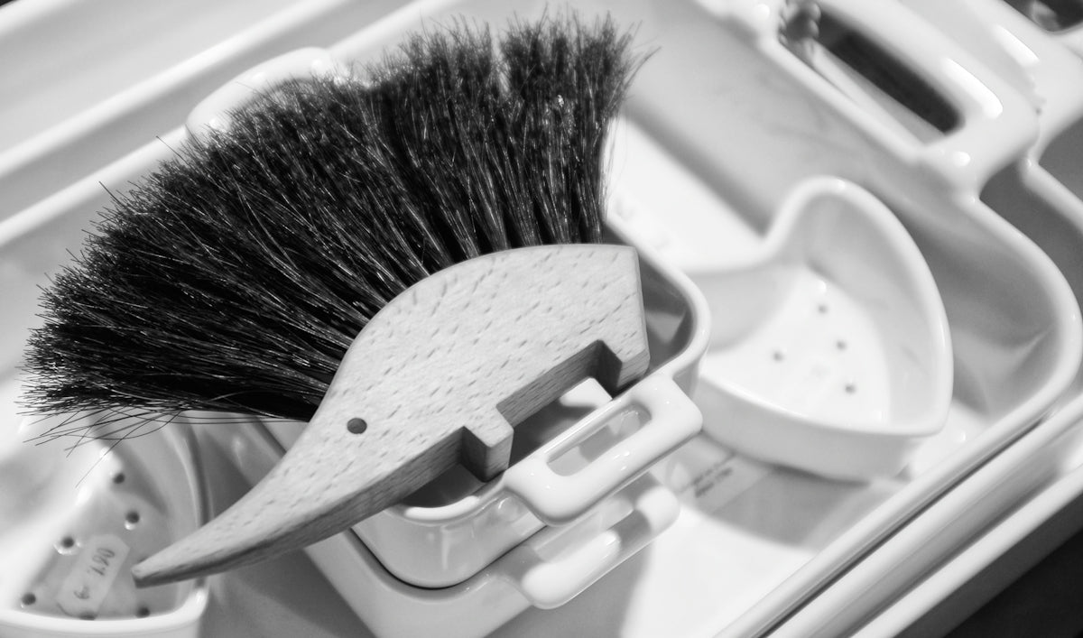 Wooden brush with black bristles in a white holder